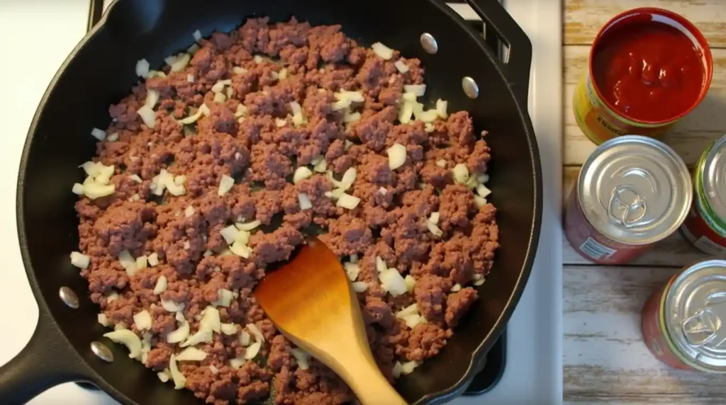 A Skillet with Ground Beef, Onion, and Tomato Sauce Cooking