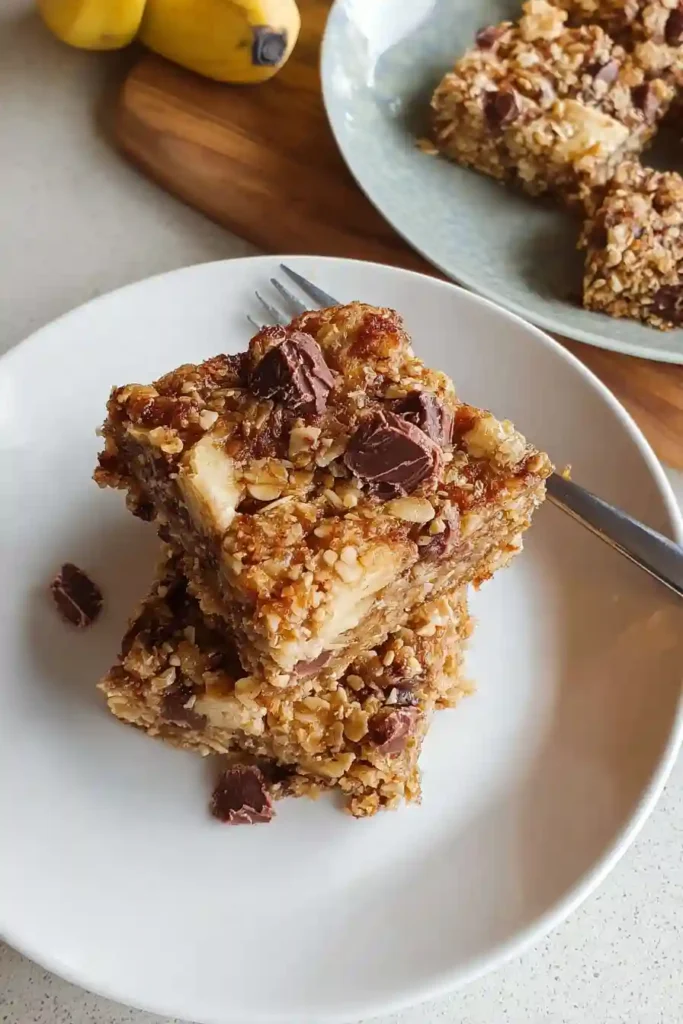 Baked banana oatmeal bars cooling completely in parchment-lined pan on wire rack before cutting