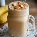 Creamy banana peanut butter smoothie in a tall glass garnished with banana slice and peanut butter drizzle