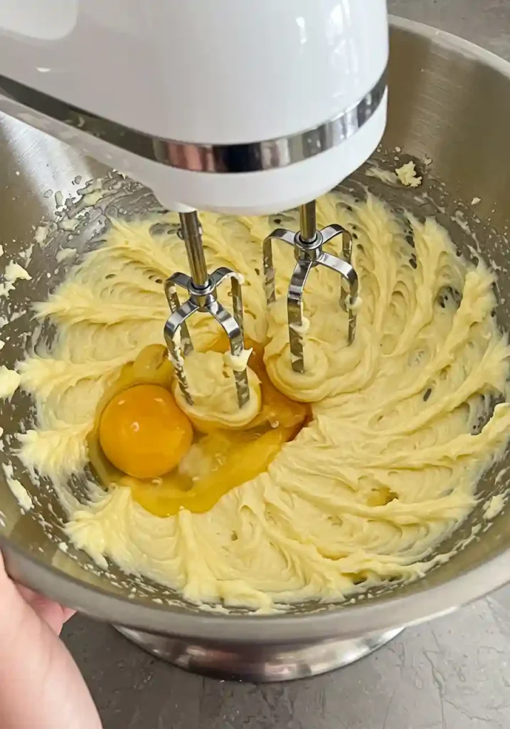 Mixing eggs and vanilla into creamed butter and sugar mixture with electric mixer for carrot muffins