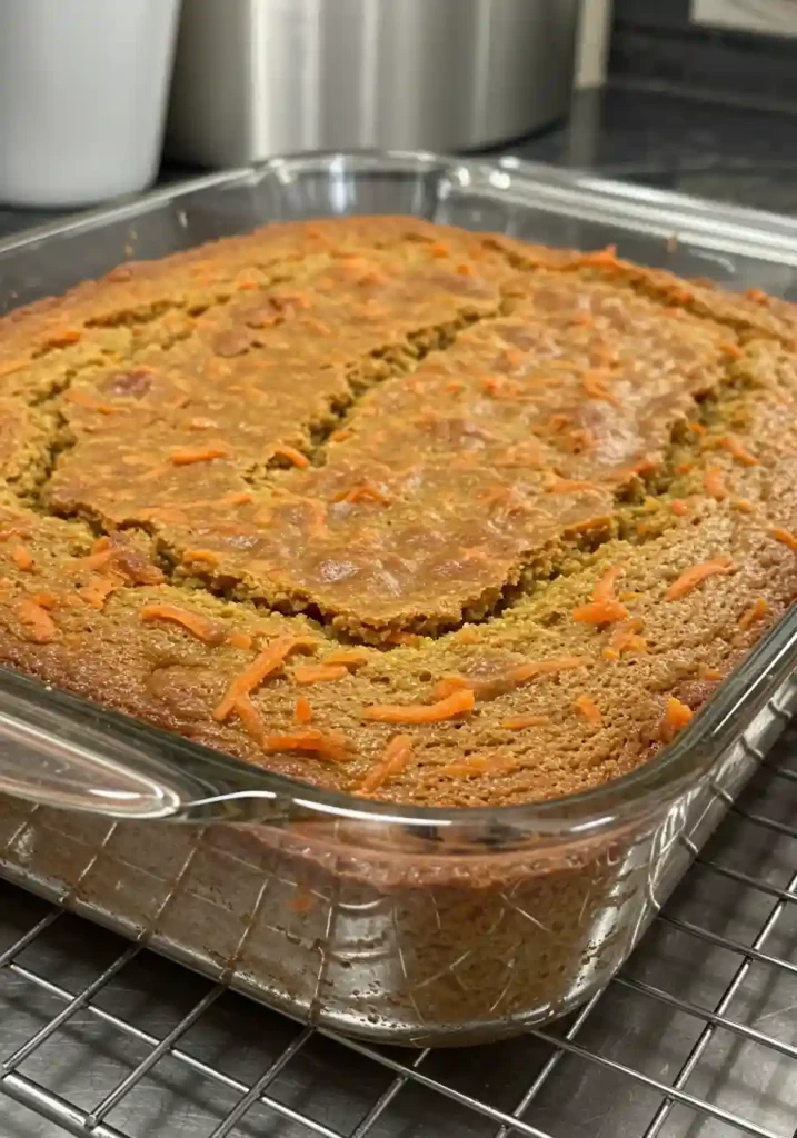 Golden brown carrot cake cooling completely in glass baking dish on wire rack