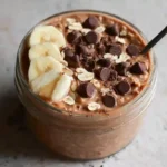 Chocolate peanut butter protein overnight oats in a mason jar with toppings