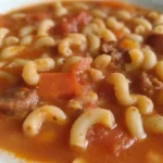 Bowl of classic beef and tomato macaroni soup garnished with parsley.