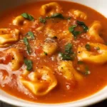 Bowl of rich Tomato Tortellini Soup garnished with basil and parmesan cheese